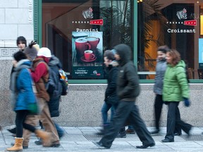 Pedestrians pass by a café in a Montreal street scene.