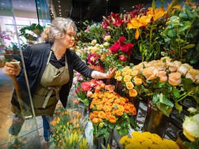 A woman adjusts flowers at a flower stall