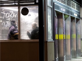 Unhoused people seen through the windows of a métro station.