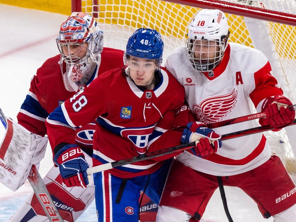 Canadiens defenceman Lane Hutson, centre, jostles with Red Wings' Andrew Copp in front of Canadiens goalie Cayden Primeau during season finale at the Bell Centre.