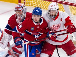 Canadiens defenceman Lane Hutson, centre in red jersey, jostles with Red Wings' Andrew Copp, right, in front of Canadiens goalie Cayden Primeau.