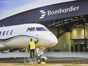A Bombardier jet sits on the tarmac in front of a hangar with the company's logo