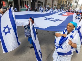 People carrying Israel flags march down a street in Montreal