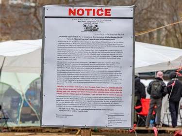 A document headlined 'NOTICE' is affixed to a post at an encampment