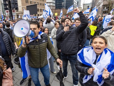 A man yells in a megaphone while surrounded by people carrying Israeli flags