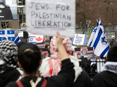 Two groups of protesters face off, with one in the foreground holding a sign reading 'Jews for Palestinian liberation' and another on the other side reading 'Bring them home now'