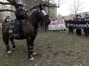 A police officer on horseback looks over his shoulder as pro-Palestinian protesters hold up banners in the background