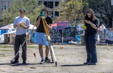 Civil engineering students Minh Nguyen, Alessandro Rocca and Olivia Zaccagnini practise surveying on the McGill University grounds.