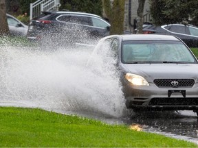 A car splashes through a puddle on LaSalle Blvd. on a rainy day in Montreal, Wednesday May 8, 2024.