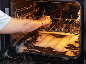 A person cleans the inside of an oven with white foam.