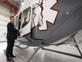 A man stands next to the open door of a medical helicopter in a hangar