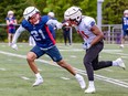 Rookie defensive-back Arthur Hamlin, in a blue jersey, is seen running stride for stride with Montreal receiver Kaion Julien-Grant, in white, during Alouettes training camp practice in St-Jérôme on Thursday.