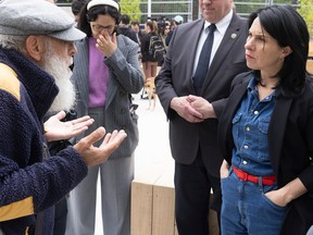 Valérie Plante, hands in her pockets, listens to an elderly man speaking while gesturing