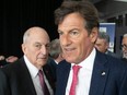A father and son stand side by side, wearing suits. They are Charles and Stephen Bronfman.