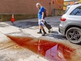 A man with a grocery cart walks past a puddle that is reddish with blood.