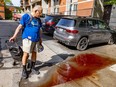 A man with a grocery cart walks past a puddle that is reddish with blood.