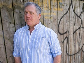 Al Goulem leans against a wooden fence