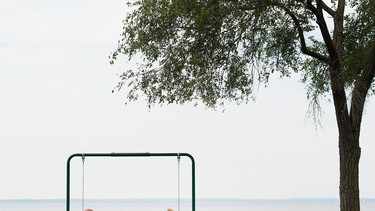 A couple relax on a swing overlooking a body of water