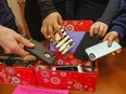 A view of children's hands placing phones in a box.