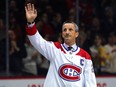 Former Canadiens captain Guy Carbonneau, in a white Habs jersey, waves to the crowd from the ice at the Bell Centre.