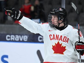 Macklin Celebrini, seen in Team Canada's white jersey at the last world junior championship, points to an unseen teammate after scoring a goal.