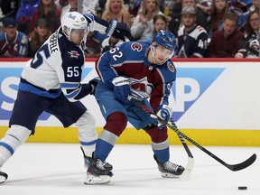 Avalanche's Artturi Lehkonen, right, has the puck on his stick as he fends off a check from the Jets' Mark Scheifele.