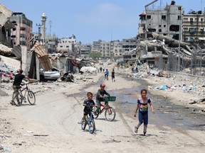Palestinian children ride their bicycles along a street devastated by Israeli bombardment in Gaza City on May 3, 2024.