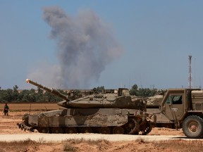 Israeli army tanks take position in southern Israel near the border with the Gaza Strip as smoke billows over Gaza during Israeli bombardment on May 7, 2024, amid the ongoing conflict between Israel and the Palestinian Hamas movement.