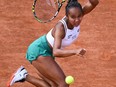 Leylah Fernandez looks at a tennis ball on a clay court with her racket behind her head