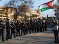 A pro-Palestinian protester holds a Palestinian flag near a line of LAPD officers outside Pomona College's commencement ceremony at Shrine Auditorium on May 12, 2024 in Los Angeles, California.