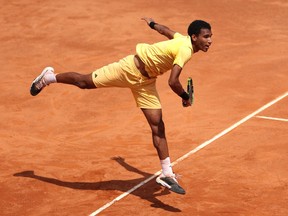 Felix Auger-Aliassime serving the ball on a clay court