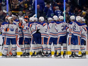 Oilers players are seen in a line congratulating one another after beating the Canucks to advance to the third round of the NHL playoffs.