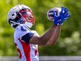 A player in an Alouettes practice uniform catches a football with both hands