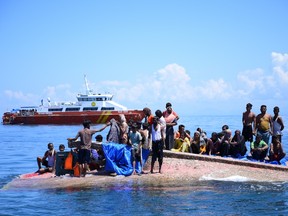 Rohingya refugees wait to be rescued from the hull of their capsized boat as a National Search and Rescue Agency (BASARNAS) vessel approaches off west Aceh on March 21, 2024.