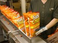 A person holds bags of chips on an assembly line.