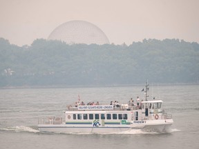 A tourist boat cruises the St. Lawrence River as smog from northern forest fires envelops the Biosphere in June 2023.