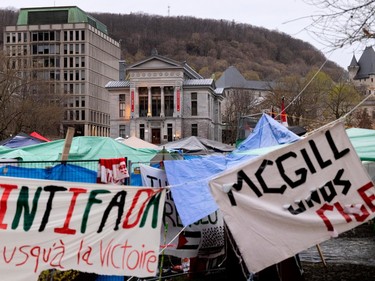 McGill University buildings are seen in the distance with an encampment and banners including 'Intifada jusqu'à la victoire', and another whose letters have partly detached, in the foreground