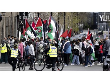 Police watch over the crowd as people slowly march through the streets of Montreal as they head to the pro-Palestinian encampment on McGill University's lower field in Montreal on Saturday, May 4, 2024.