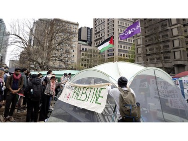 People hang an Academics for Palestine banner on a tent at the pro-Palestinian encampment on McGill's lower field in Montreal on Saturday, May 4, 2024.