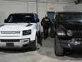 An Ontario Provincial Police officer walks between two recovered stolen vehicles during a news conference in Montreal, Wednesday, April 3, 2024.