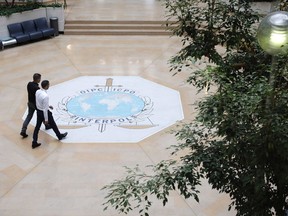 People walk on the Interpol logo of the international police agency in Lyon, central France.