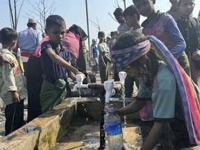 Rohingya refugee children collect drinking water after a midnight fire raced through their refugee camp at Kutupalong in Cox's Bazar district, Bangladesh, Sunday, Jan. 7, 2024.