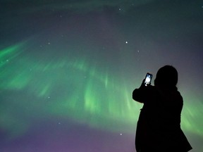 A person takes a photo of the northern lights in Vancouver, on Saturday, May 11, 2024.