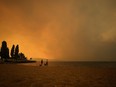 Smoke from the McDougall Creek wildfire fills the air and nearly blocks out the sun as people take in the view of Okanagan Lake from Tugboat Beach, in Kelowna, B.C., on Aug. 18, 2023.