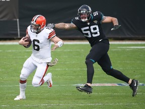 A football player wearing number 59 extends his arm to another player wearing number 6 who is running while holding a football
