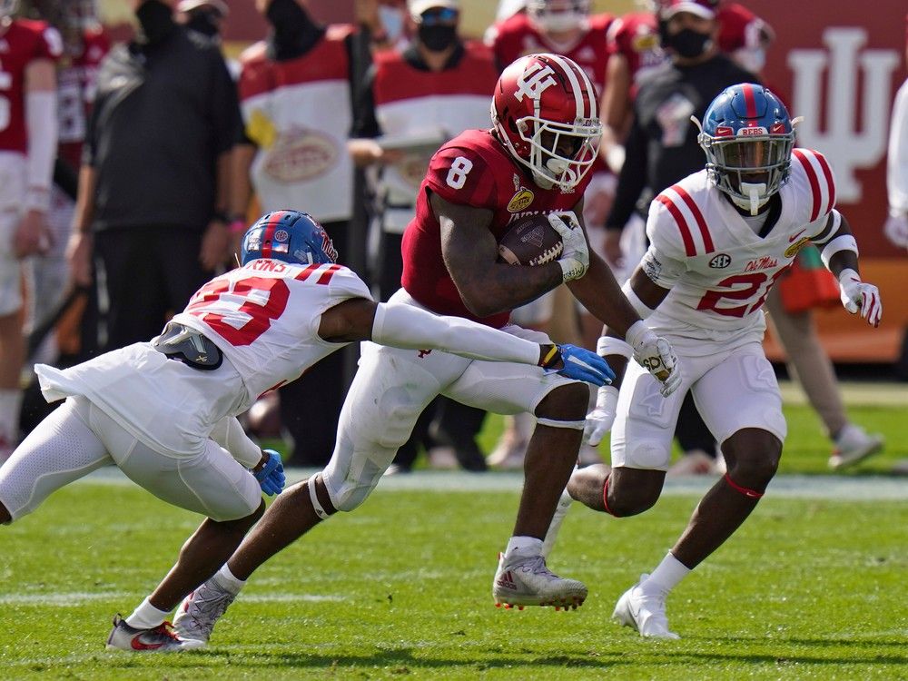 Indiana running-back Stevie Scott III slips between Mississippi defensive-back Jakorey Hawkins, left, and defensive-back A.J. Finley during game in 2021. 