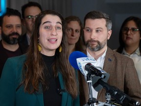 Émilise Lessard-Therrien speaks at a podium with Gabriel Nadeau-Dubois and several other people behind her