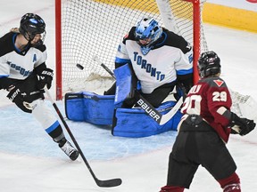 Marie-Philip Poulin, right in Montreal's burgundy jersey, is seen firing a shot to the right of Toronto goaltender Kristen Campbell, who is hugging the left post, while Toronto's Renata Fast, left, looks on.