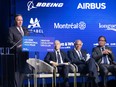 François Legault speaks in front of a background with the logos for Boeing and Airbus as other dignitaries watch on