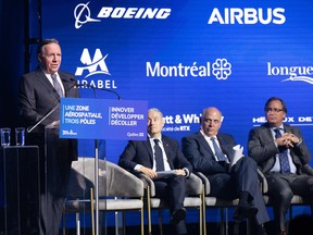 François Legault speaks in front of a background with the logos for Boeing and Airbus as other dignitaries watch on